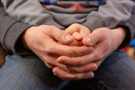 Junge und Erwachsener halten ihre zum Gebet verschränkten Hände ineinander.